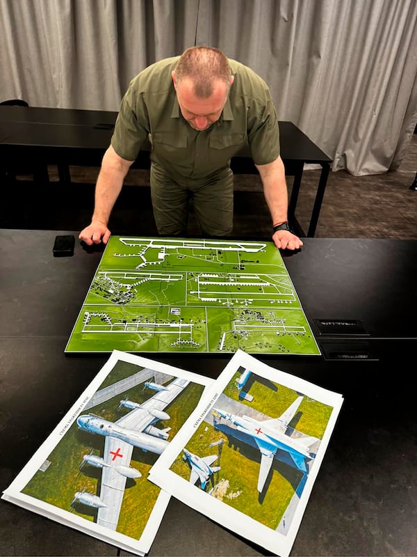In this undated photo provided by the Ukrainian Security Service, head of the Security Service Vasyl Malyuk studies a photo of a map of Russia's strategic aviation location in his office in Ukraine. (Ukrainian Security Service via AP)