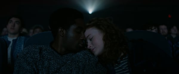 Lucas (Caleb McLaughlin) and Max (Sadie Sink) cuddle and kiss while sitting in seats F11 and F12 inside Atlanta’s Tara Theatre during the “Stranger Things” series finale. (Netflix)