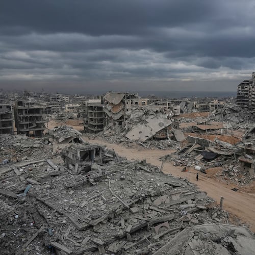 Displaced Palestinians walk amid destroyed buildings in the Shati refugee camp in Gaza City, Sunday, Oct. 12, 2025, after Israel and Hamas agreed to a pause in their war and the release of the remaining hostages. (AP Photo/Abdel Kareem Hana)