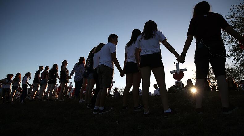 PARKLAND, FL - FEBRUARY 18: Students and family members holds hands around a makeshift memorial in front of Marjory Stoneman Douglas High School where 17 people were killed on February 14, on February 18, 2018 in Parkland, Florida. (Photo by Mark Wilson/Getty Images)