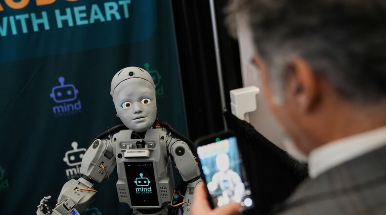 A man records a humanoid robot inside the exhibition room at the Humanoids Summit, Thursday, Dec. 11, 2025, in Mountain View, Calif. (AP Photo/Godofredo A. Vásquez)