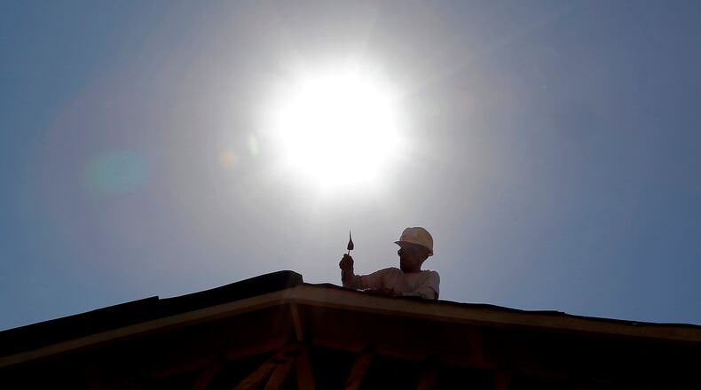 In this July 25, 2014 file photo, a roofer works under the mid-day sun in Gilbert, Ariz.
