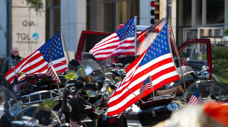 Motorcycles and American flags are lined up on Peachtree Street waiting for the start of a previous Veterans Day Parade in Atlanta. (AJC file)
