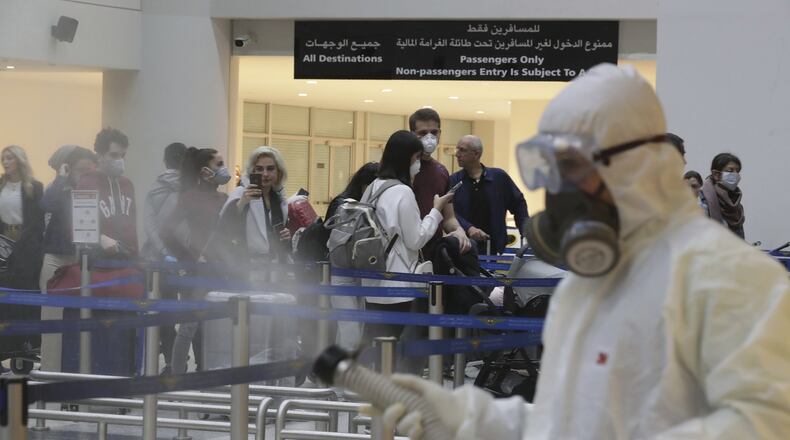 Passengers line up as workers wearing protective gear spray disinfectant as a precaution against the coronavirus outbreak, in the departure terminal at the Rafik Hariri International Airport, in Beirut, Lebanon, Thursday, March 5, 2020. The novel coronavirus has infected more than 80,000 people globally, causing around 2,700 deaths, mainly in China. (AP Photo/Hassan Ammar)