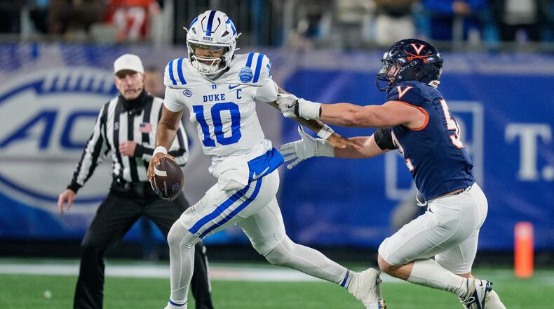 FILE - Virginia defensive lineman Daniel Rickert (52) tries to tackle Duke quarterback Darian Mensah (10) during the Atlantic Coast Conference championship NCAA college football game between Virginia and Duke, Dec. 6, 2025, in Charlotte, N.C. (AP Photo/Jacob Kupferman, File)