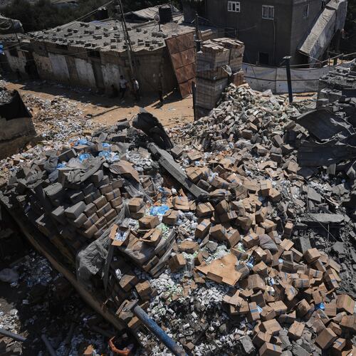 Palestinians walk past a food-aid warehouse damaged in an Israeli airstrike that targeted a nearby house in Deir al-Balah, central Gaza Strip, Wednesday, Aug. 26, 2026. (AP Photo/Abdel Kareem Hana)