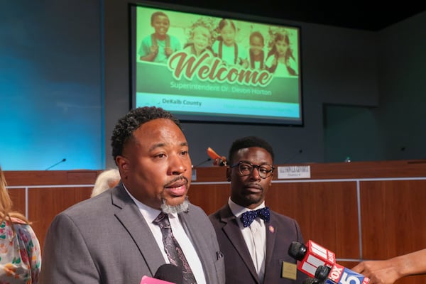 With a welcome sign in the background, Devon Horton (left) talks with members of the media after the DeKalb County Board of Education hired him for the superintendent position in 2023. To his left is Diijon DaCosta. (Jason Getz/AJC)
