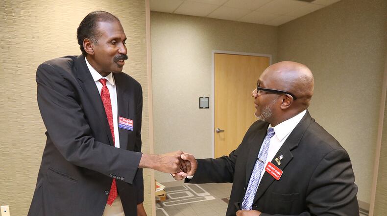 Candidates for the DeKalb County Commission Randal Mangham (left) and Greg Adams shake hands as they arrive for a debate at the Tucker-Reid H. Cofer Library on Tuesday. Curtis Compton/ccompton@ajc.com