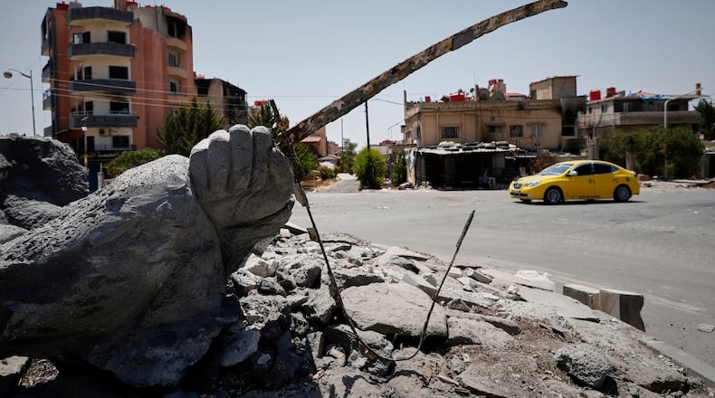FILE - A car drives by a destroyed statue in the Druze-majority town of Sweida, Syria, Friday, July 25, 2025. (AP Photo/Omar Sanadiki, File)