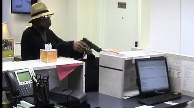 The robber then jumped over the teller counter with a black canvas bag in his other hand and began gathering money from several of the teller drawers.