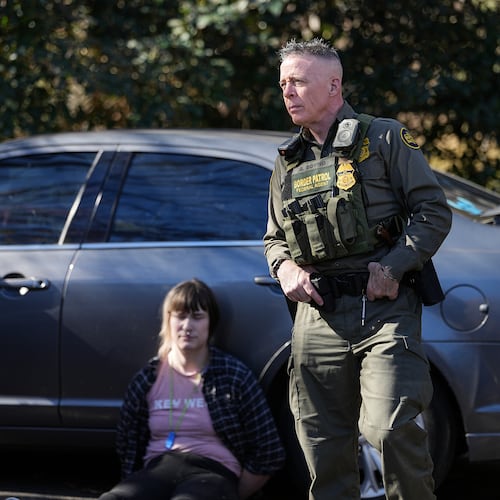 U.S. Border Patrol Commander at large Gregory Bovino, right, looks on as a detainee sits by a car, Monday, Nov. 17, 2025, in Charlotte, N.C. (AP Photo/Matt Kelley)