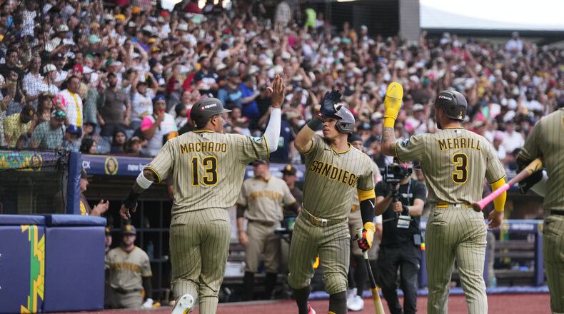 San Diego Padres' Manny Machado, left, is congratulated after scoring against the Arizona Diamondbacks during the seventh inning of a baseball game in Mexico City, Saturday, April 25, 2026. (AP Photo/Fernando Llano)