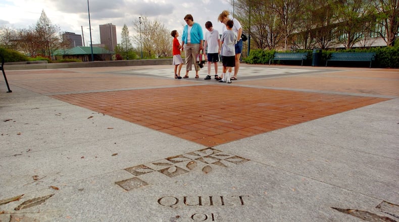 In 2005 in Atlanta’s Centennial Olympic Park, visitors view the “Quilt of Remembrance” memorial marking thefatal bombing during the 1996 Olympics. AJC FILE PHOTO