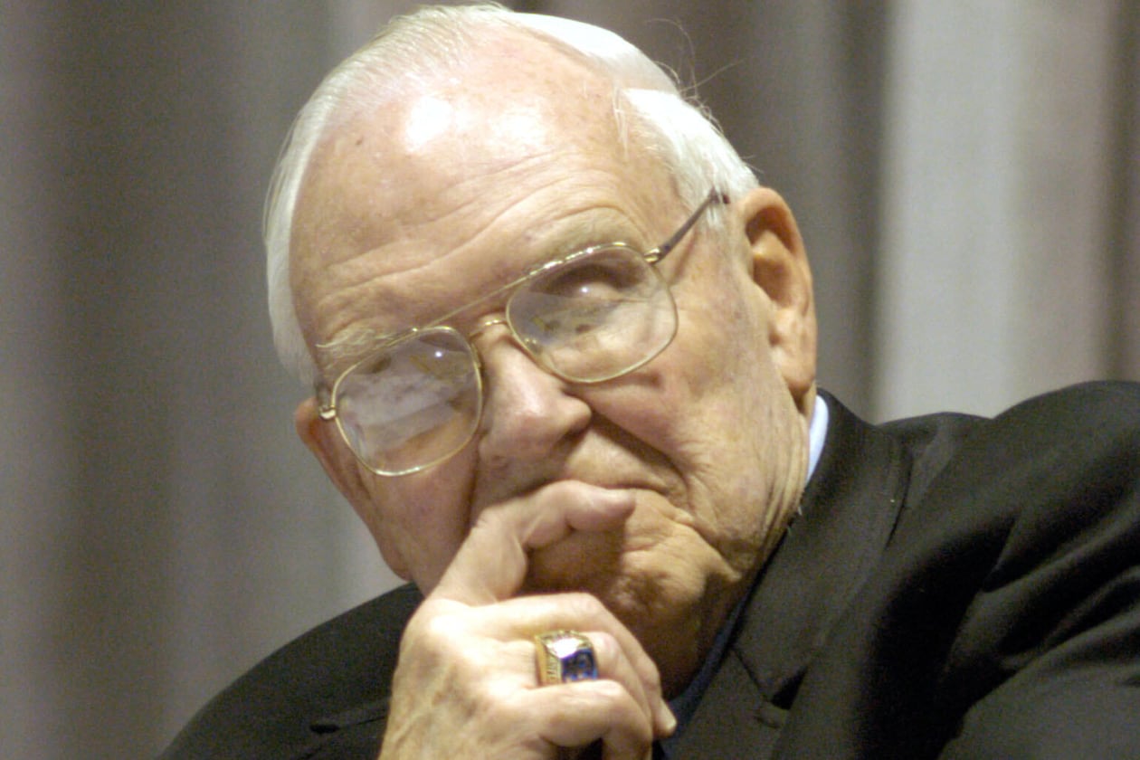 FILE - Roy Kramer, former commissioner , Southeastern Conference, listens to Mack Brown, Head Football Coach for The University of Texas, during his opening statement for the panel discussion for "Ethical Issues in College Athletics" in the Daniel-Meyer Coliseum on the Texas Christian University Campus, Thursday, Feb., 12, 2004. (AP Photo/David Pellerin, File)