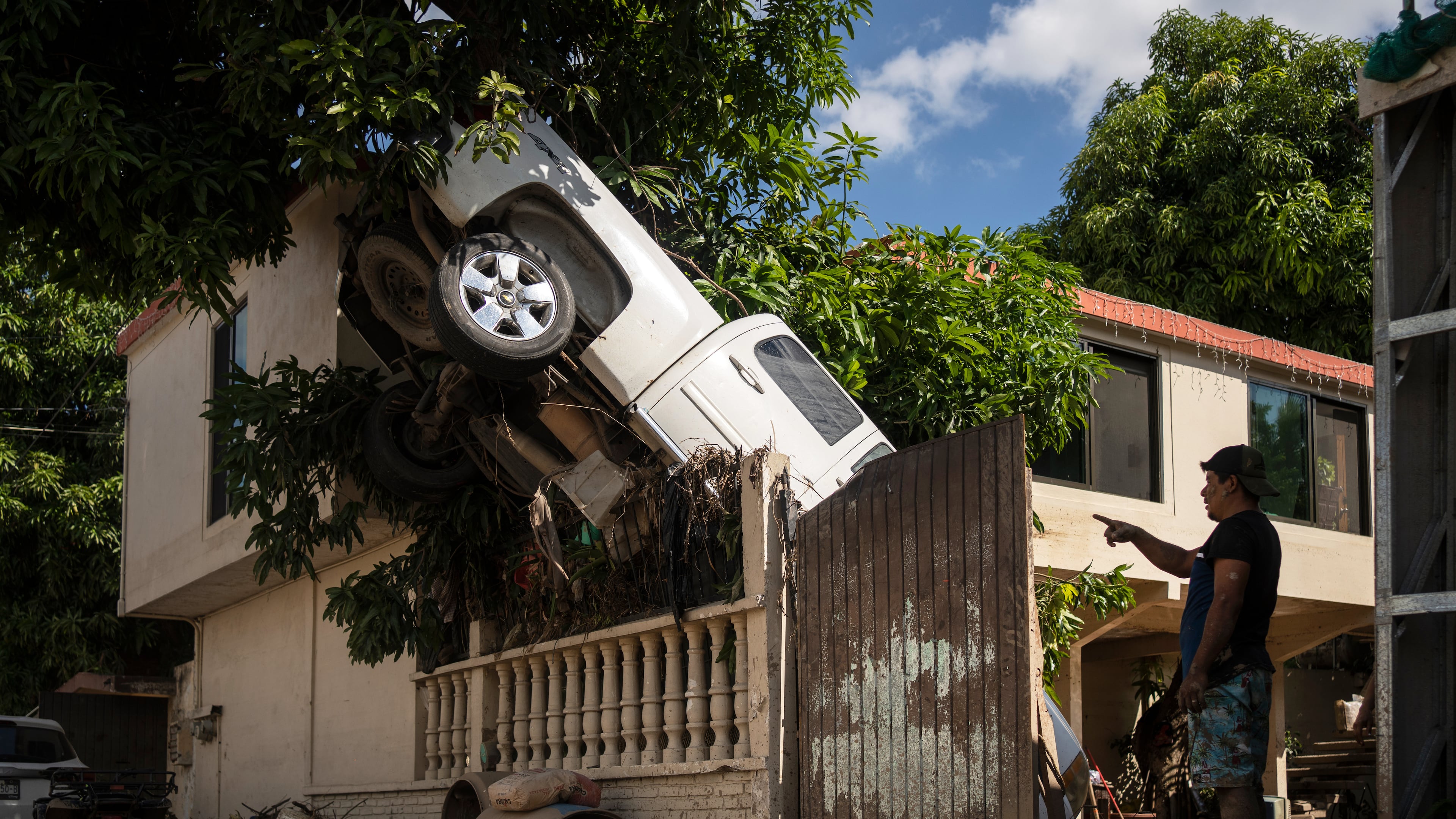 A pickup truck hangs over a fence in Poza Rica, Veracruz state, Mexico, Sunday, Oct. 12, 2025, after rain and flooding. (AP Photo/Felix Marquez)
