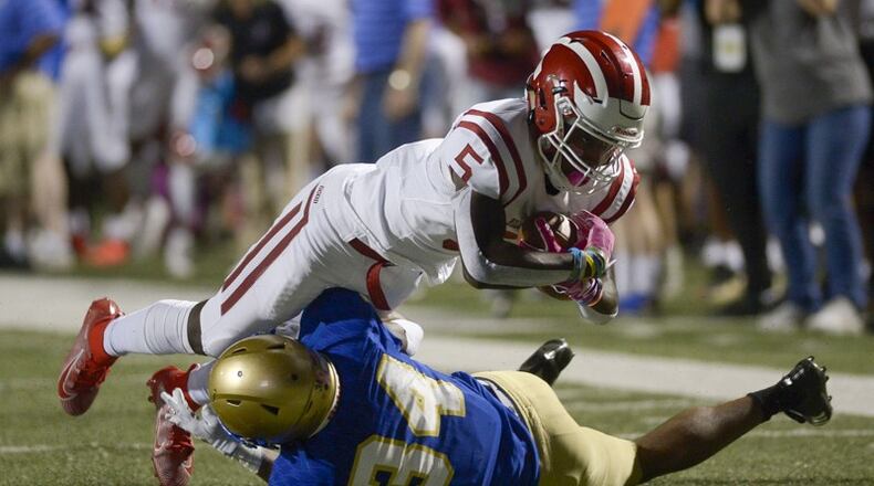 McEachern defensive back Victor Okafor (24) makes a tackle on Hillgrove wide receiver Braylen Howard (5) as he runs the ball in the first half of Friday's game at McEachern.