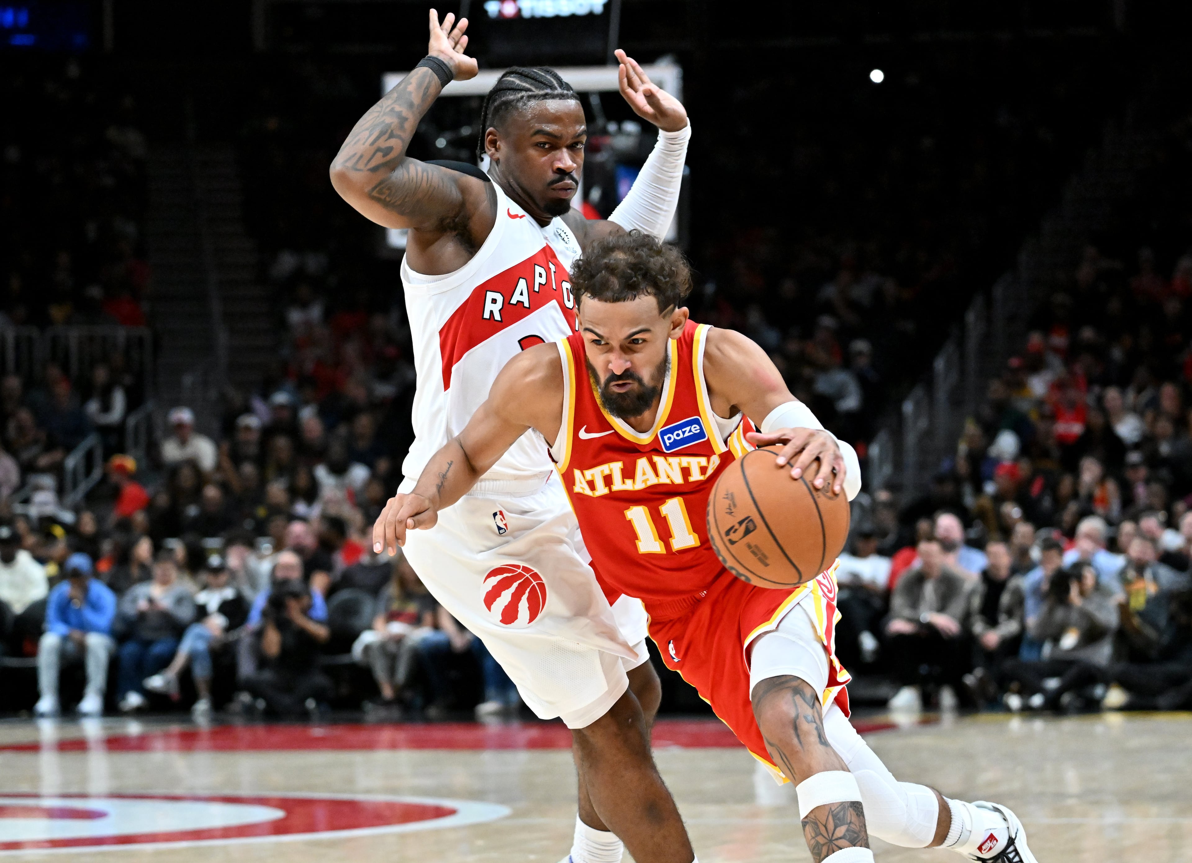 Atlanta Hawks guard Trae Young (11) drives past Toronto Raptors guard Jamal Shead (23) during the second half in the home opener at State Farm Arena, Thursday, October 22, 2025, in Atlanta. Toronto Raptors won 138-118 over Atlanta Hawks. (Hyosub Shin / AJC)