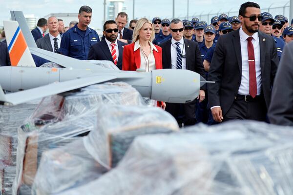 U.S. Attorney General Pam Bondi and FBI Director Kash Patel walk past pallets of shrink-wrapped narcotics and a drone used in the investigations as they arrive for a news conference on Wednesday, April 9, 2025, at Port Everglades, Fla. (Amy Beth Bennett /South Florida Sun-Sentinel via AP)