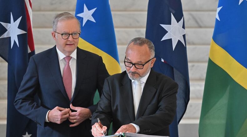 Solomon Islands' Prime Minister Matthew Wale, right, signs a visitors book as Australian Prime Minister Anthony Albanese watches at Parliament House in Canberra, Wednesday, June 3, 2026. (Mick Tsikas/AAP Image via AP)