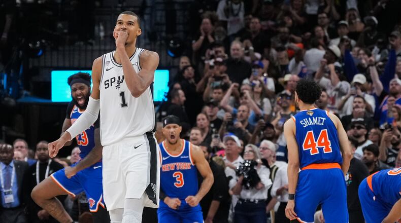 San Antonio Spurs forward Victor Wembanyama walks off the court as time expires during the second half of Game 2 of the NBA Finals basketball series as New York Knicks guard Landry Shamet (44), guard Josh Hart (3), and center Mitchell Robinson (23) celebrate, Friday, June 5, 2026, in San Antonio. (AP Photo/Eric Gay)