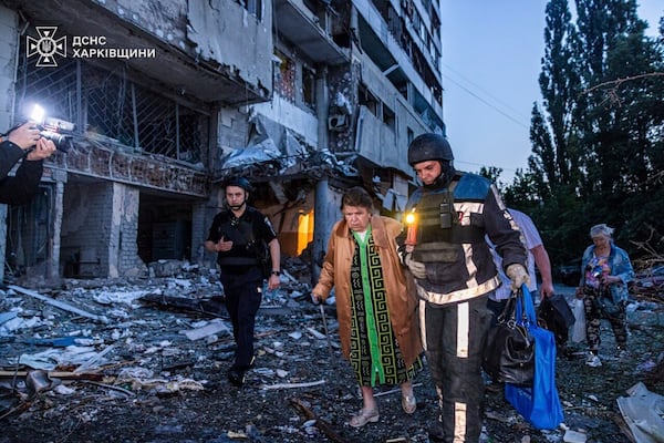 In this photo provided by the Ukrainian Emergency Services on Thursday, June 12, 2025, a rescue worker evacuates a woman from a building which was damaged by a Russian strike in Kharkiv, Ukraine. (Ukrainian Emergency Services via AP)