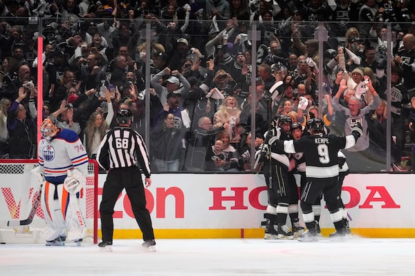 Members of the Los Angeles Kings, right, celebrate a goal by left wing Andrei Kuzmenko as Edmonton Oilers goaltender Stuart Skinner stands in goal during the first period in Game 1 of an NHL hockey first-round playoff series Monday, April 21, 2025, in Los Angeles. (AP Photo/Mark J. Terrill)