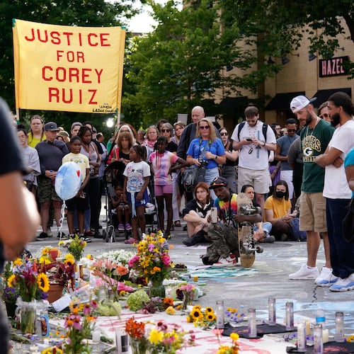 People gather near a memorial at the site where a man was shot and killed on Wednesday by Madison police, Thursday, July 23, 2026, in Madison, Wis. (AP Photo/Kayla Wolf)