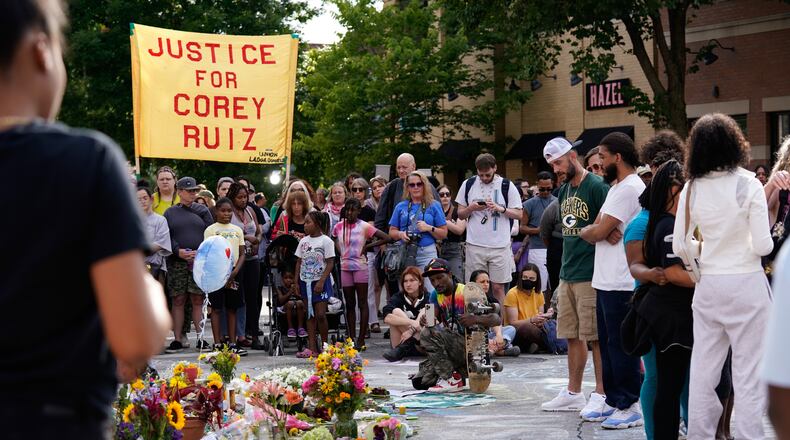 People gather near a memorial at the site where a man was shot and killed on Wednesday by Madison police, Thursday, July 23, 2026, in Madison, Wis. (AP Photo/Kayla Wolf)