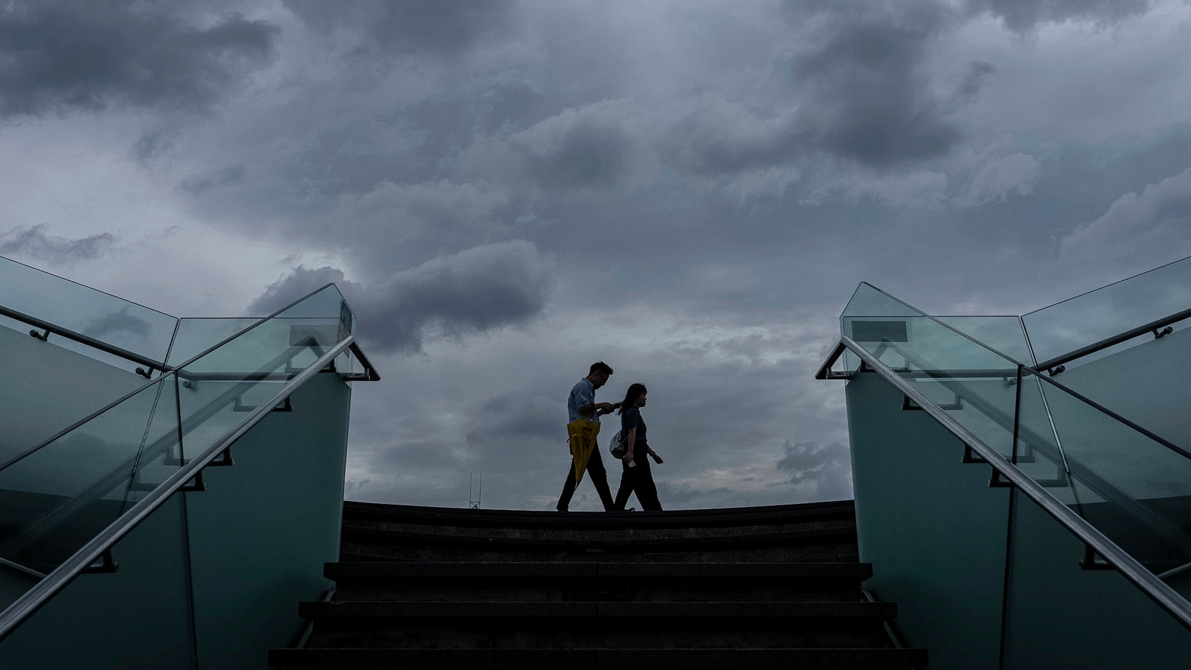 Pedestrians walk along the waterfront of Victoria Harbor ahead of Super Typhoon Ragasa approaches Hong Kong, Tuesday, Sept. 23, 2025. (AP Photo/Chan Long Hei)