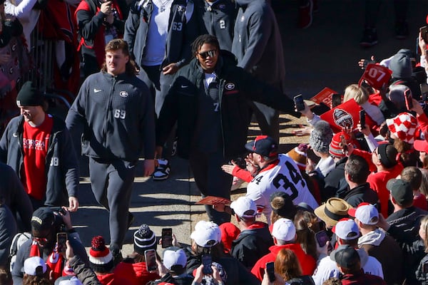 Georgia offensive lineman Devin Willock (77, center wearing glasses) walks with fellow offensive lineman Tate Ratledge (69, left) and others during the Dawg Walk in the 2022 National Championship Celebration on Saturday at Sanford Stadium. (Jason Getz / Jason.Getz@ajc.com)