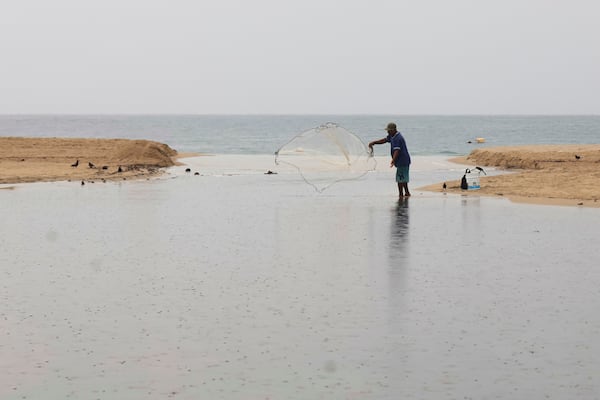 A fisherman throws a net in Puerto Escondido, Oaxaca state, Mexico, before the arrival of Hurricane Erick, Wednesday, June 18, 2025. (AP Photo/Luis Alberto Cruz)