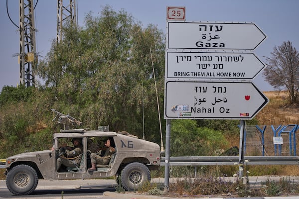 Israeli army vehicle pass by a new sign pointing towards Gaza reading "To release Omri Miron go straight" near Kibbutz Nahal Oz in southern Israel, where Miron was kidnapped from on Oct. 7, on Sunday, June 1, 2025. (AP Photo/Ohad Zwigenberg)