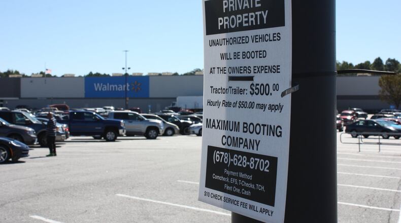 Signs in the Newnan Crossing shopping center in Newnan, Ga., warn owners of ‘unauthorized vehicles’ that they are subject to booting.