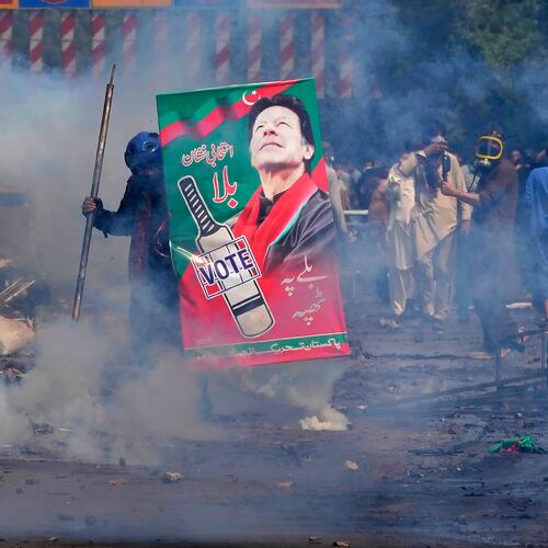 FILE - Supporters of former Prime Minister Imran Khan take cover after riot police officers fire tear gas to disperse them during clashes, in Lahore, Pakistan, Wednesday, March 15, 2023. (AP Photo/K.M. Chaudary, File)