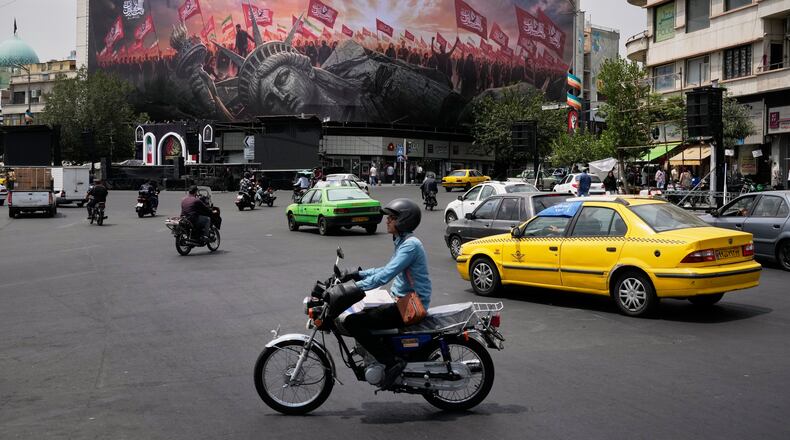 Vehicles travel past a billboard depicting a fallen Statue of Liberty and crowds carrying Iranian and Shiite flags at Revolution Square in Tehran, Iran, Monday, Aug. 3, 2026. (AP Photo/Vahid Salemi)