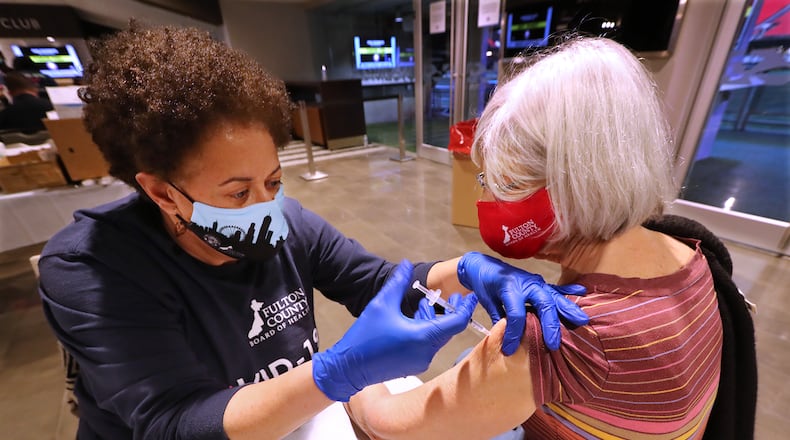 Dr. Lynn Paxton (left), District Health Director of the Fulton County Board of Health, administers a Pfizer vaccine to Karen Schaefer at the mass vaccination site at Mercedes-Benz Stadium on Wednesday. (Curtis Compton / Curtis.Compton@ajc.com)