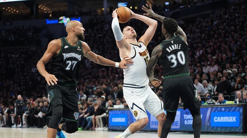 Denver Nuggets center Nikola Jokic (15) works toward the basket as Minnesota Timberwolves center Rudy Gobert (27) and forward Julius Randle (30) defend during the first half in Game 3 of a first-round NBA basketball playoff series, Thursday, April 23, 2026, in Minneapolis. (AP Photo/Abbie Parr)