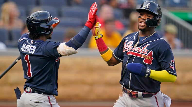Atlanta Braves' Ronald Acuna Jr., right, is greeted by Ozzie Albies after scoring on a double by Freddie Freeman during the first inning of a baseball game in Pittsburgh, Monday, July 5, 2021. (AP Photo/Gene J. Puskar)