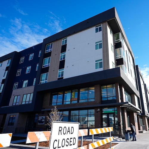 FILE - A person sweeps outside during the grand opening of the Rose on Colfax, a new affordable housing community with a co-located childcare center in the East Colfax neighborhood, Jan. 24, 2024, in Denver. (AP Photo/David Zalubowski, File)