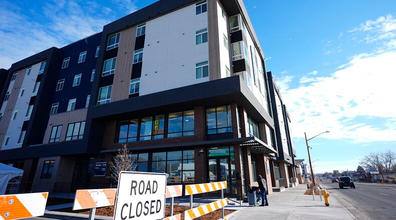 FILE - A person sweeps outside during the grand opening of the Rose on Colfax, a new affordable housing community with a co-located childcare center in the East Colfax neighborhood, Jan. 24, 2024, in Denver. (AP Photo/David Zalubowski, File)