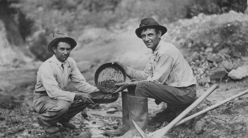 Original caption: "1933 -- The Jenkins brothers of Dahlonega, Tom (left) and William, busy with their gold pans in the famed mining section around their home. There was twenty-five cents' worth of ore in the gravel which William scooped up in his pan."