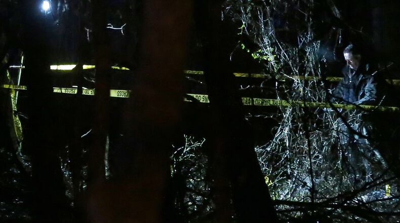 An investigator works at the scene where the body of a shooting victim was found in a wooded section of Creel Park in south Fulton County on Monday, Jan. 4, 2016. Ben Gray / bgray@ajc.com