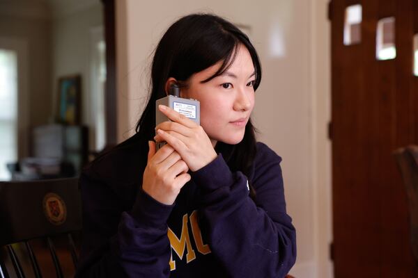 Emory University researcher Jiyoung Hwang listens to hear if a sensor is on before handing it over to study participant Henry Slack at his Decatur home on Tuesday, Aug. 5, 2025. (Natrice Miller/AJC)