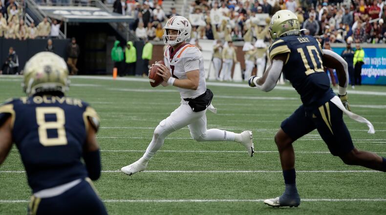 Virginia Tech quarterback Braxton Burmeister, center, looks to pass against Georgia Tech's Tobias Oliver (8) and Ayinde Eley (10) during the first half of an NCAA college football game Saturday, Oct. 30, 2021, in Atlanta. (AP Photo/Ben Margot)