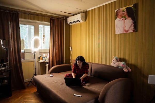 Olha Kurtmalaieva works with a computer sitting on a sofa at her apartment in Kyiv, Ukraine, on Tuesday, June 17, 2025. (AP Photo/Evgeniy Maloletka)