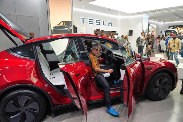 Media personnel look at the Tesla's Model Y car at the newly opened India's first Tesla showroom in Mumbai, India, Tuesday, July 15, 2025. (AP Photo/Rafiq Maqbool)
