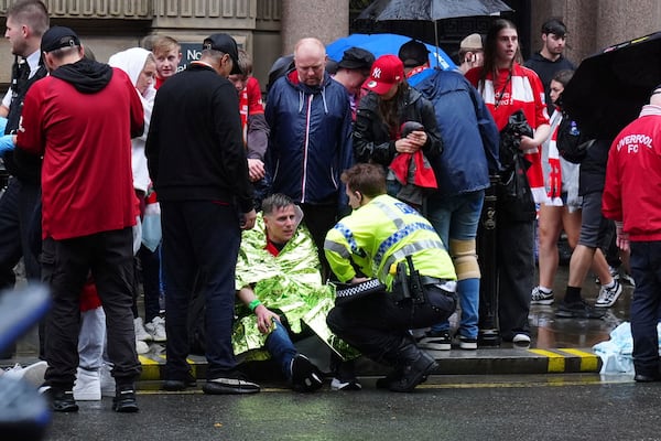 A police officer speaks with a man at the site of an incident on Water Street near the Liver Building in Liverpool after a car collided with pedestrians during the Premier League winners parade, in Liverpool, England, Monday May 26, 2025. (Owen Humphreys/PA via AP)