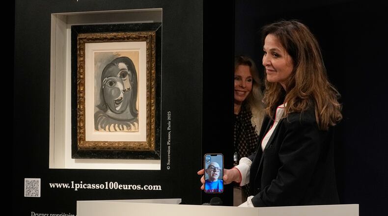Peri Cochin, right, founder of "1 Picasso for 100 euros," speaks on the phone with the winner, Ari Hodara of Paris, next to the painting 'Head of a Woman' by Pablo Picasso, painted in 1941, after the raffle draw at Christie's in Paris, Tuesday, April 14, 2026, in support of Alzheimer's research. (AP Photo/Michel Euler)