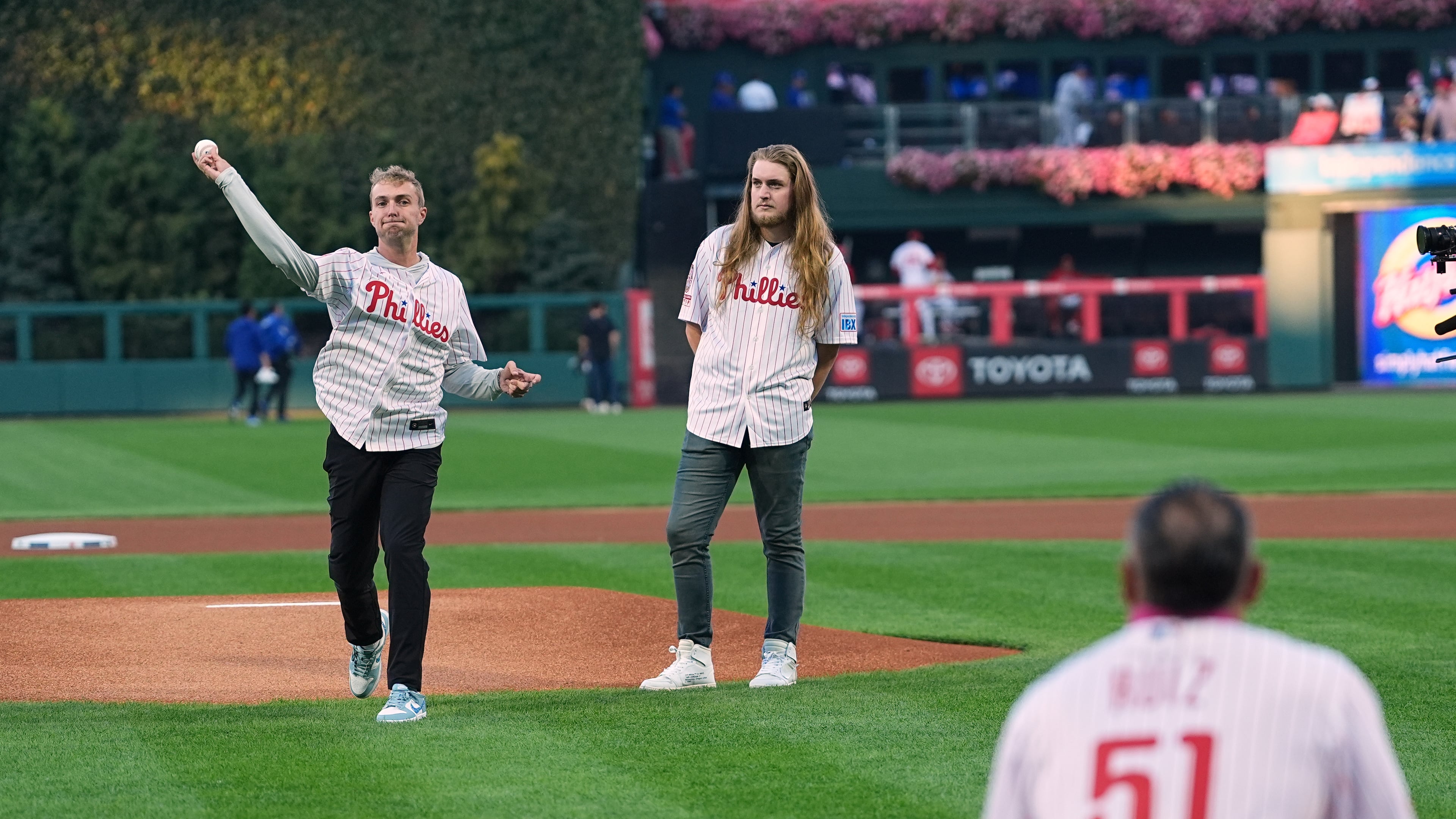CORRECTS FIRST NAME TO RYAN, NOT MATT - Braden Halladay, left, accompanied by his brother Ryan Halladay, throws a ceremonially first pitch to former Philadelphia Phillies catcher Carlos Ruiz, marking the 15th anniversary of their father Roy Halladay's postseason no-hitter, ahead of Game 2 of baseball's National League Division Series between the Phillies and the Los Angeles Dodgers, Monday, Oct. 6, 2025, in Philadelphia. (AP Photo/Matt Rourke)