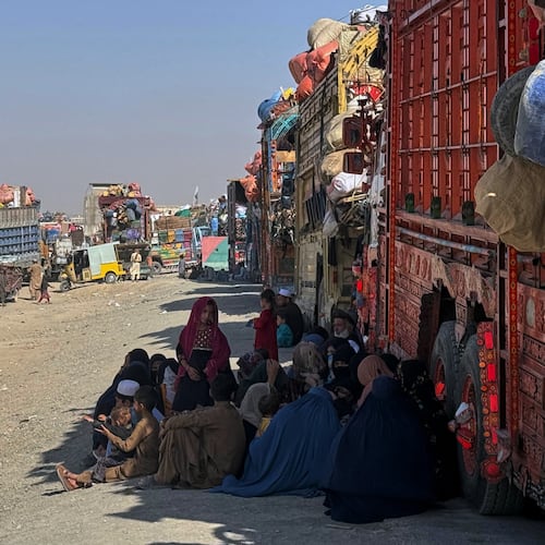 Afghan refugees sit beside trucks loaded with their belongings as they wait their turn to leave for their homeland through a border crossing point which partially opens following Oct.19 ceasefire on the outskirts of Chaman, a border town on the Pakistan Afghan border, Wednesday, Oct. 29, 2025. (AP Photo/H. Achakzai)